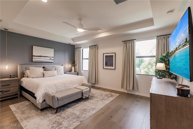 13005 Pembroke Dr, Naples, FL 34105 - bedroom with wood finished floors, multiple windows, and a raised ceiling
