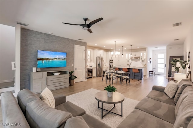 13005 Pembroke Dr, Naples, FL 34105 - living area featuring an accent wall, a ceiling fan, light wood finished floors, and visible vents