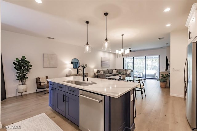 13005 Pembroke Dr, Naples, FL 34105 - kitchen featuring a center island with sink, appliances with stainless steel finishes, a sink, light wood-type flooring, and open floor plan