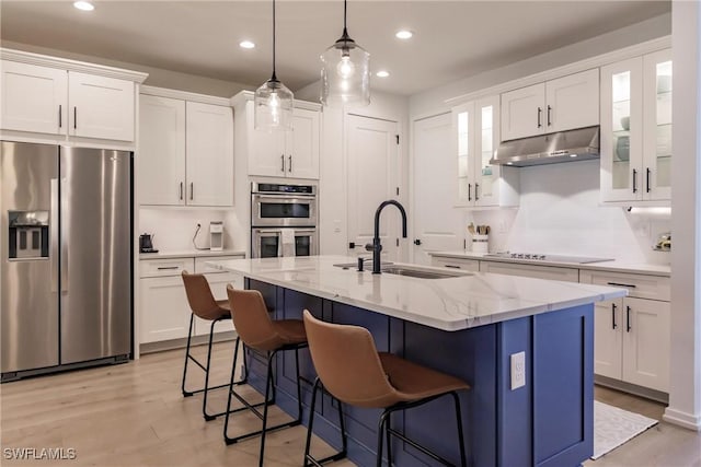 13005 Pembroke Dr, Naples, FL 34105 - kitchen featuring under cabinet range hood, white cabinetry, a sink, and appliances with stainless steel finishes
