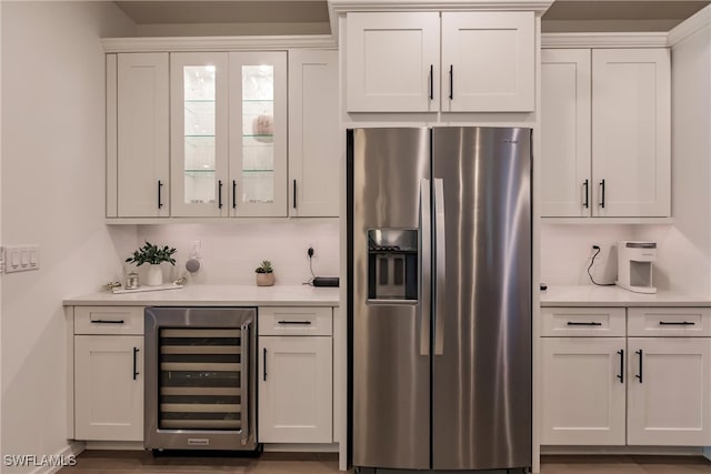 13005 Pembroke Dr, Naples, FL 34105 - kitchen with light countertops, stainless steel fridge, beverage cooler, white cabinets, and glass insert cabinets