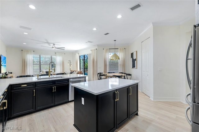 kitchen with light countertops, dark cabinetry, a sink, and appliances with stainless steel finishes