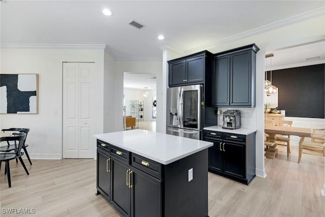 kitchen with light countertops, stainless steel refrigerator with ice dispenser, visible vents, light wood-style floors, and ornamental molding