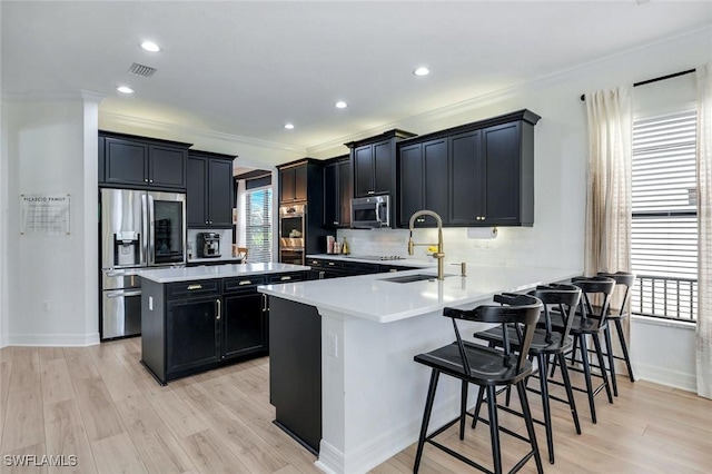 kitchen featuring light countertops, visible vents, stainless steel appliances, a sink, and dark cabinetry