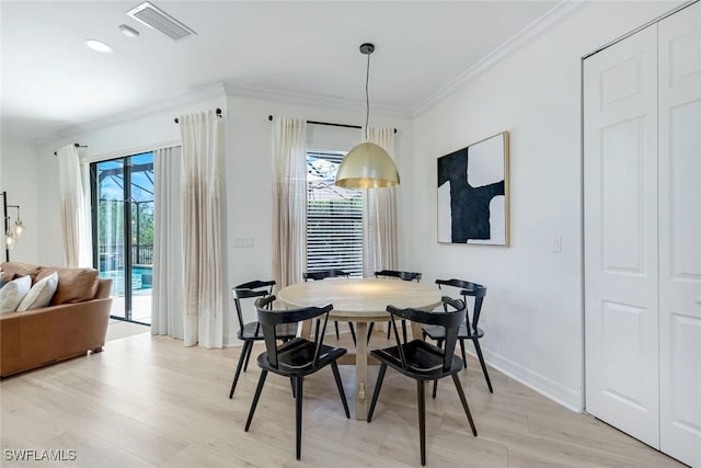 dining space featuring light wood finished floors, a wealth of natural light, visible vents, and crown molding