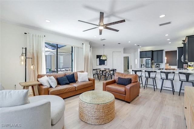 living room with visible vents, ornamental molding, recessed lighting, a ceiling fan, and light wood-type flooring
