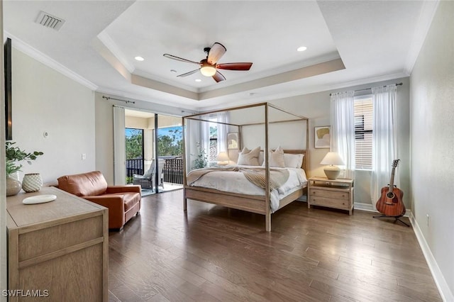 bedroom featuring dark wood-type flooring, a tray ceiling, and visible vents