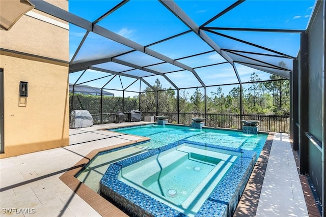 view of swimming pool featuring glass enclosure, a pool with connected hot tub, and a patio area