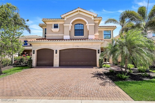 mediterranean / spanish-style house featuring stucco siding, a tiled roof, and decorative driveway
