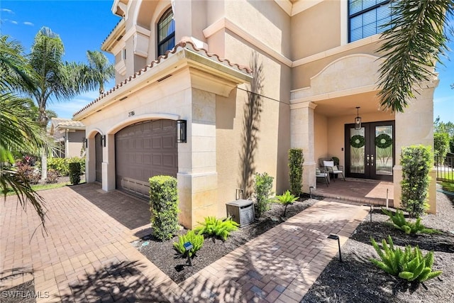 doorway to property featuring french doors, a garage, and stucco siding