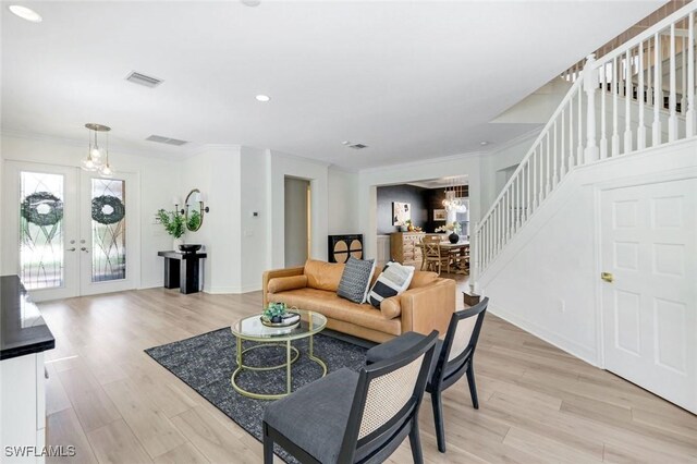 living area featuring light wood-type flooring, crown molding, stairway, and visible vents
