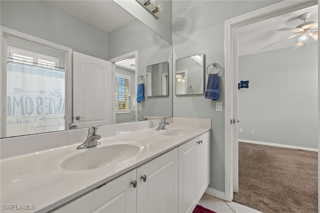 bathroom featuring double vanity, ceiling fan, a sink, and baseboards