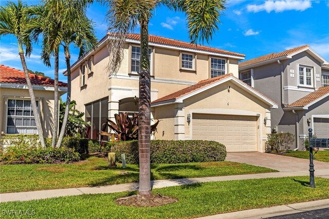 mediterranean / spanish-style house featuring a tile roof, stucco siding, a front yard, and concrete driveway