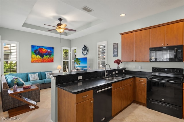 kitchen featuring a tray ceiling, a sink, a peninsula, open floor plan, and black appliances