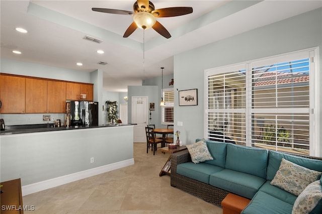 living room featuring a tray ceiling, recessed lighting, light tile patterned floors, visible vents, and a ceiling fan