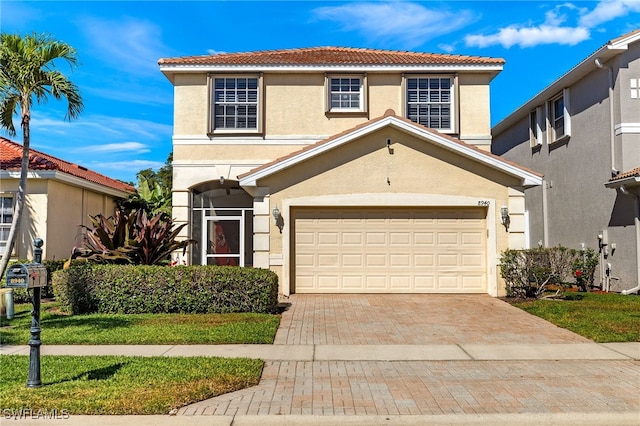 traditional home featuring a tile roof, a garage, decorative driveway, and stucco siding
