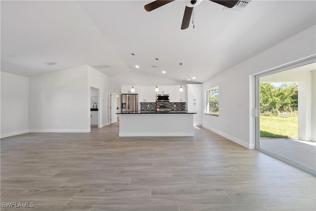 kitchen featuring open floor plan, backsplash, dark countertops, ceiling fan, and appliances with stainless steel finishes