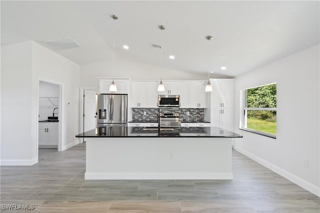 kitchen featuring white cabinetry, dark countertops, appliances with stainless steel finishes, and decorative backsplash