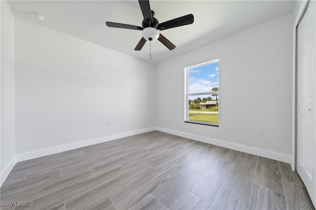 spare room with a ceiling fan, light wood-style floors, and baseboards