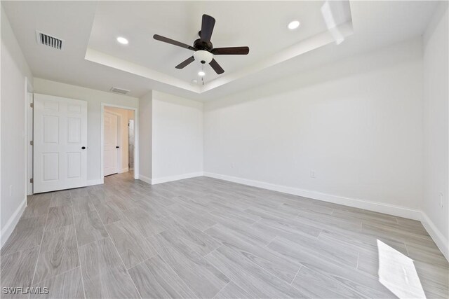 empty room with baseboards, visible vents, recessed lighting, and a raised ceiling