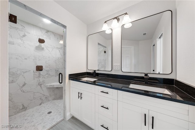 bathroom featuring double vanity, a sink, and a marble finish shower
