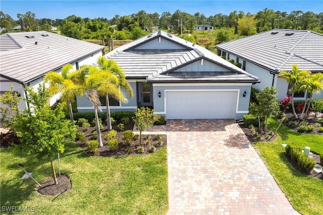 ranch-style home with a tile roof, decorative driveway, a front lawn, and an attached garage