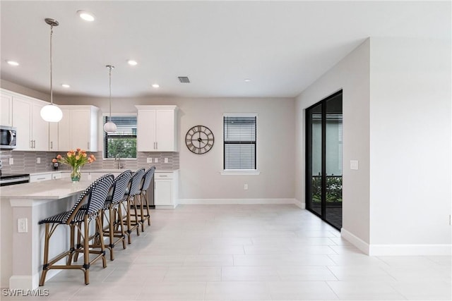 kitchen featuring light countertops, a breakfast bar area, stainless steel appliances, a center island, and backsplash