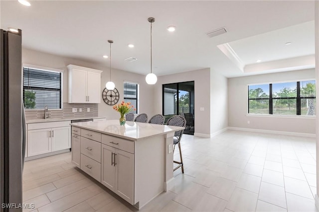 kitchen with a kitchen bar, a center island, backsplash, a sink, and freestanding refrigerator