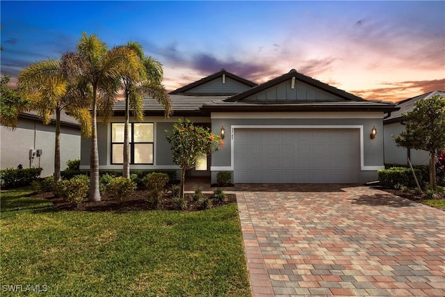 view of front of house with stucco siding, a garage, a yard, and decorative driveway
