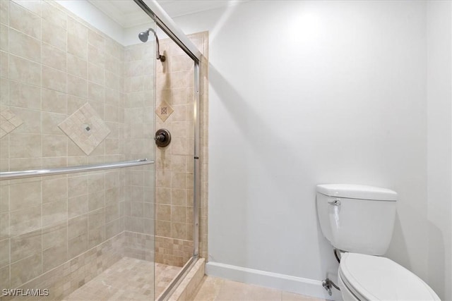 bathroom with baseboards, toilet, tile patterned floors, and a shower stall