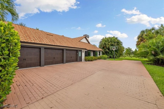 exterior space with a tile roof, decorative driveway, and an attached garage