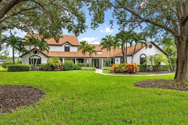 view of front of property featuring a front lawn, stucco siding, and a tiled roof