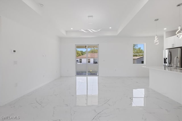 1508 Hibiscus Ave, Lehigh Acres, FL 33972 - unfurnished living room with a tray ceiling, a wealth of natural light, marble finish floor, and recessed lighting