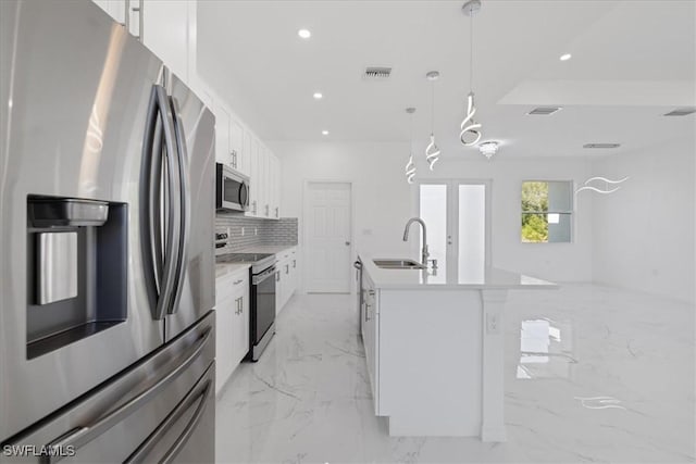 1508 Hibiscus Ave, Lehigh Acres, FL 33972 - kitchen featuring marble finish floor, a sink, white cabinets, a kitchen island with sink, and appliances with stainless steel finishes