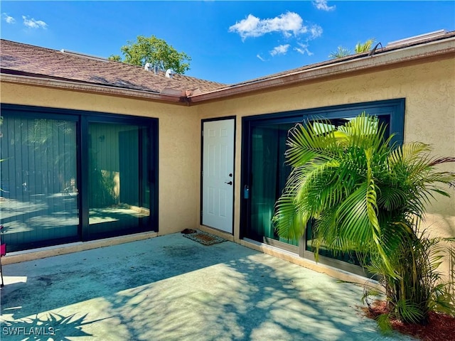 17304 Timber Oak Ln, Fort Myers, FL 33908 - property entrance with stucco siding, roof with shingles, and a patio