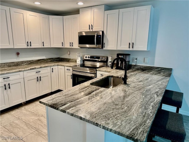 17304 Timber Oak Ln, Fort Myers, FL 33908 - kitchen featuring white cabinets, a peninsula, appliances with stainless steel finishes, a sink, and stone counters