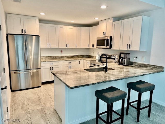 17304 Timber Oak Ln, Fort Myers, FL 33908 - kitchen featuring a peninsula, appliances with stainless steel finishes, white cabinetry, a sink, and stone countertops