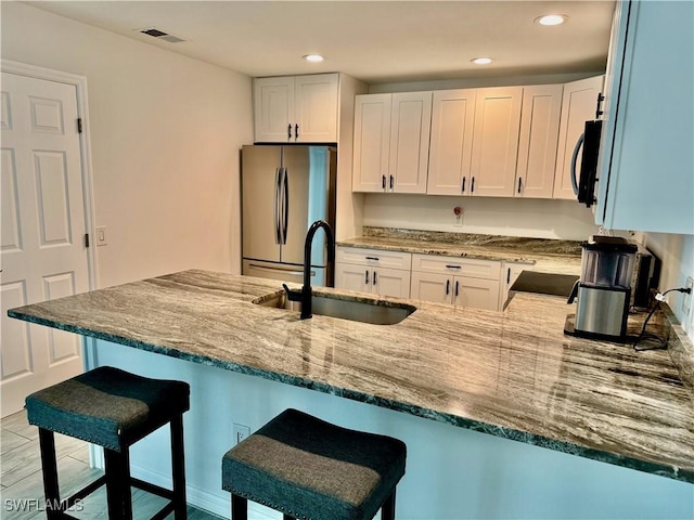 17304 Timber Oak Ln, Fort Myers, FL 33908 - kitchen featuring a sink, stone counters, visible vents, freestanding refrigerator, and a peninsula