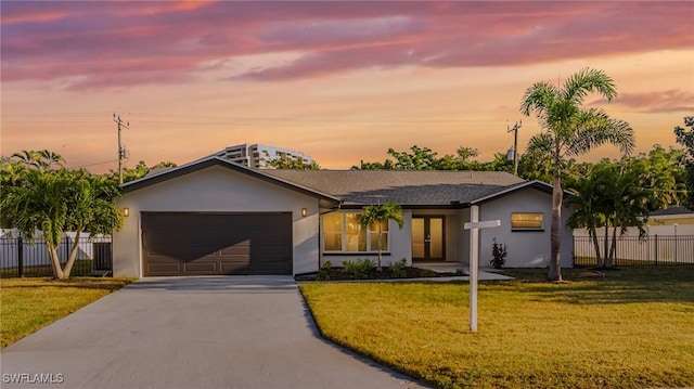 ranch-style house with french doors, driveway, fence, a yard, and stucco siding