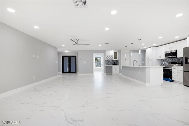 unfurnished living room with marble finish floor, baseboards, and recessed lighting