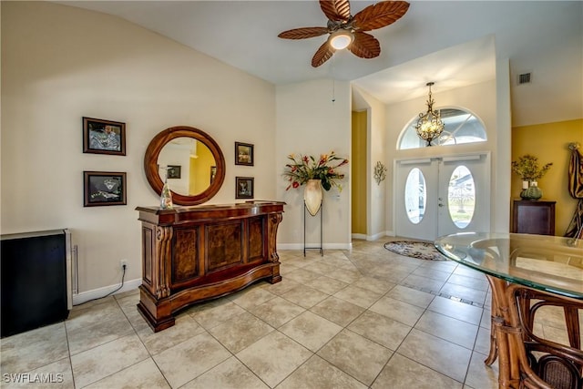 foyer entrance featuring french doors, ceiling fan with notable chandelier, baseboards, light tile patterned flooring, and visible vents