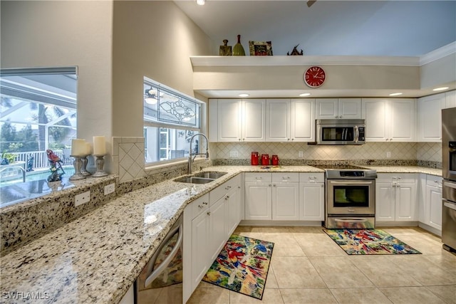 kitchen featuring a sink, white cabinetry, light stone countertops, and appliances with stainless steel finishes
