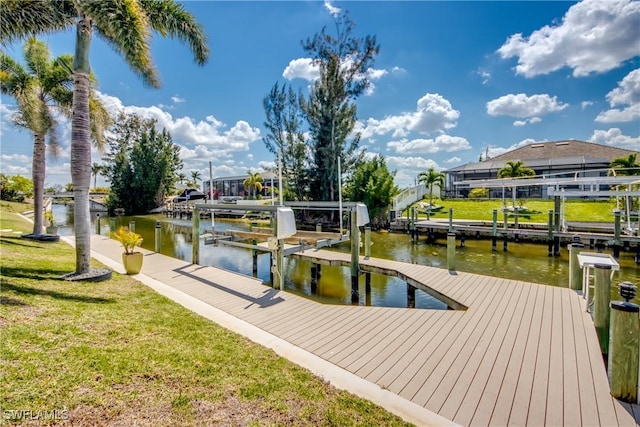 dock area featuring boat lift, a water view, and a yard