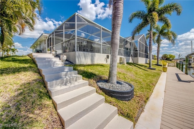 exterior space featuring stairs, a lanai, a boat dock, and a lawn