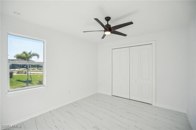 203 Old Burnt Store Rd S, Cape Coral, FL 33991 - unfurnished bedroom featuring a closet, marble finish floor, baseboards, and a ceiling fan