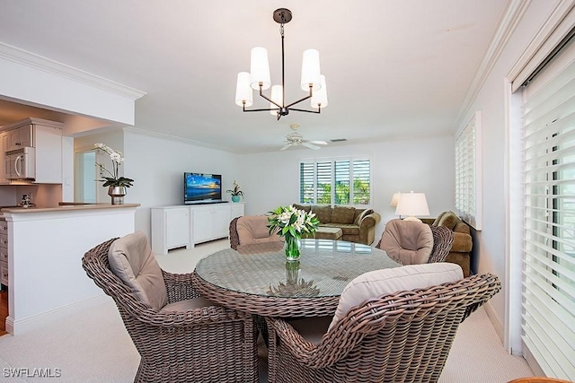 dining room with crown molding, ceiling fan with notable chandelier, and light carpet