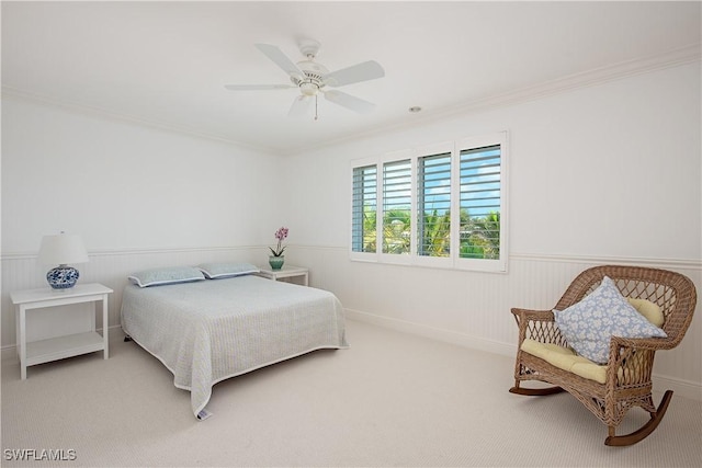 carpeted bedroom with wainscoting, ornamental molding, and a ceiling fan