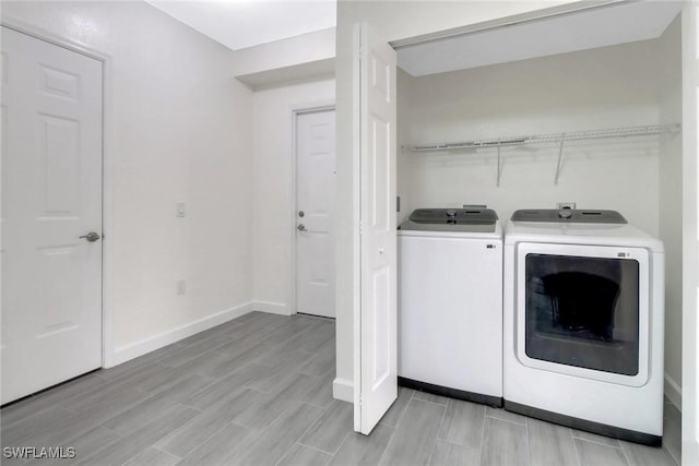 laundry room with washer and dryer, laundry area, baseboards, and wood tiled floor