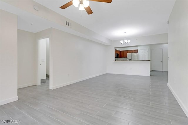 unfurnished living room with ceiling fan with notable chandelier, baseboards, and visible vents
