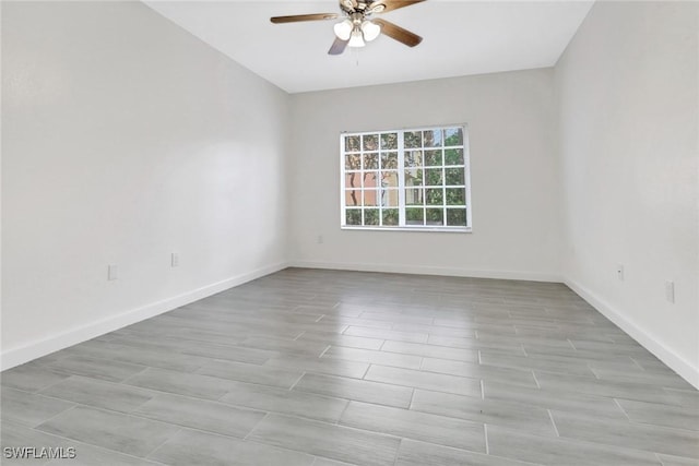 empty room with ceiling fan, light wood finished floors, and baseboards
